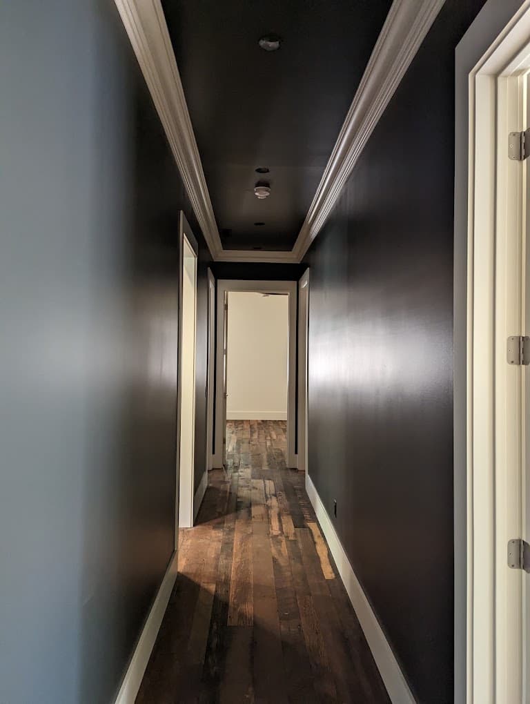 The same crossing ceiling beams seen from a different angle, dark stained wood against a white vaulted ceiling with recessed lighting.